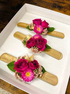 three pink flowers are placed on top of each other in a white box with gold trim