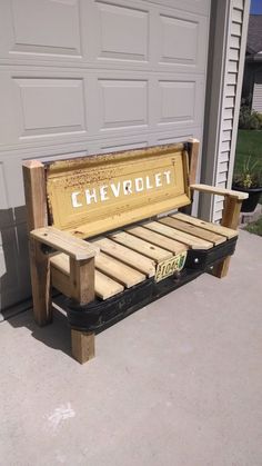 a bench made out of pallets sitting in front of a garage door with the word chevrolet written on it