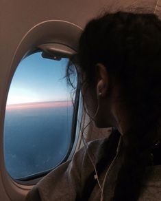 a woman looking out an airplane window at the ocean