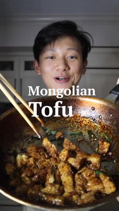 a young boy is cooking tofu in a wok