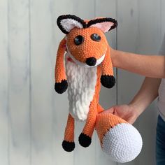 a person holding an orange and white stuffed animal on a string with a ball in it's hand