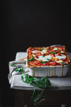 a square pizza sitting on top of a table next to a green leafy plant