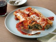 a white plate topped with lasagna covered in sauce and cheese next to a fork