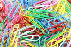 many different colored paper clips are stacked together