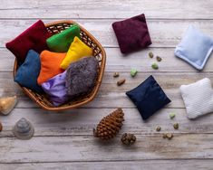 a basket filled with different colored towels next to pine cones and other items on top of a wooden table