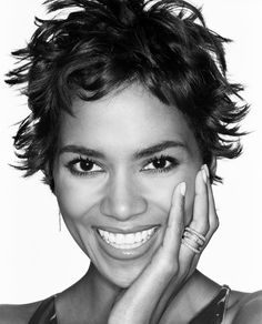 a black and white photo of a smiling woman with her hands on her chins