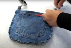 someone is using scissors to cut out the pocket of a pair of jeans that they are holding