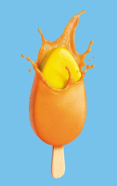 an orange lollypop with a lemon in the center and splashing liquid on top