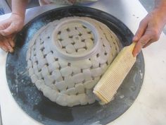 a person is using a brush to clean a white object on a plate that has been made out of clay