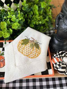 a table topped with plates and napkins next to a vase filled with green plants