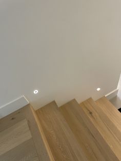 an empty room with wood floors and white walls in the corner, looking up at stairs