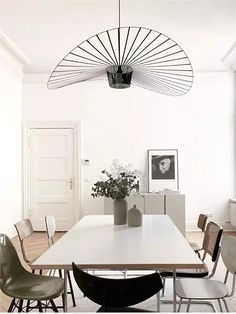 a dining room table with chairs around it and a vase on the table in front of it