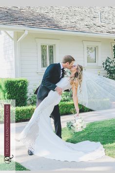 a bride and groom kissing in front of a house