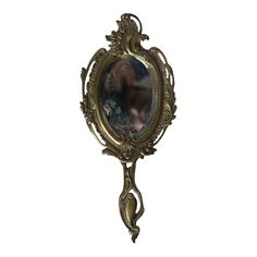 an ornate gold framed mirror with a woman's face in the center, on a white background