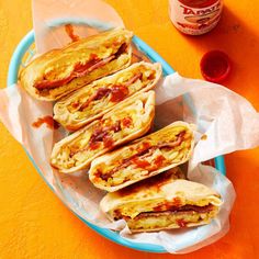 there are four sandwiches in the basket on the table next to some ketchup