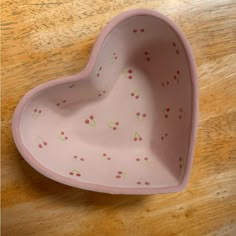 a pink heart shaped bowl sitting on top of a wooden table