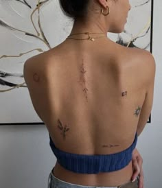 a woman with tattoos on her back standing in front of a painting