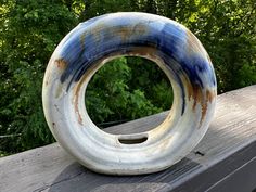 an odd shaped object sitting on top of a wooden table in front of some trees