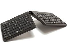 two black keyboards sitting next to each other on a white surface and one is open