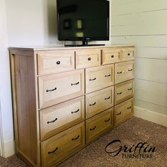 a flat screen tv sitting on top of a wooden dresser next to a white wall