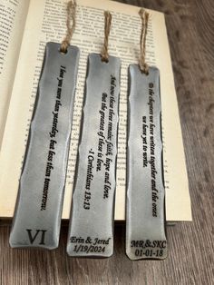 three bookmarks with names on them are sitting next to an open book and string