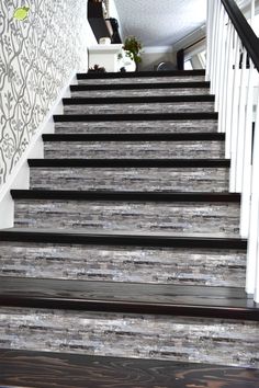 the stairs are painted white and black with wood treading on them, along with decorative wallpaper