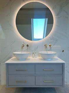 a bathroom with two sinks and a round mirror