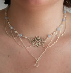 This necklace features delicate pastel blue beads, lustrous pearls, and draped chains, creating a layered, fairy and ethereal look. In the heart of this necklace, a captivating moth pendant and a sparkling clear crystal pendant add a touch of timeless beauty.  The layers of draped chains add depth and dimension to the necklace, allowing it to rest gracefully against your neckline, accentuating your natural beauty. The delicate nature of this piece ensures it is suitable for any occasion, from casual outings to formal events, making it a versatile addition to your jewellery collection. Elevate your style with this exquisite accessory, effortlessly blending sophistication with a touch of enchantment.  The pastel blue beads interspersed between the pearls create a harmonious colour palette. T Ethereal Handmade Silver Necklaces, Handmade White Ethereal Necklace, Mystical Handmade Blue Necklaces, Handmade Mystical Blue Necklace, Silver Fairy Necklace, Diy Necklace Designs, Handmade Butterfly Fairycore Necklaces, Ethereal Fairy, Moth Necklace