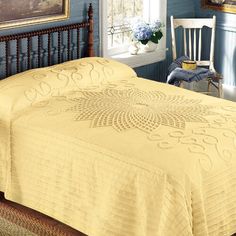 a bed with a yellow bedspread in a blue room next to a window