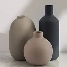 three vases are sitting on a marble surface