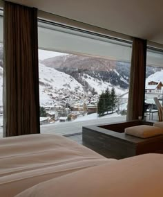 a bedroom with two beds and a large window overlooking the snow covered mountain side town