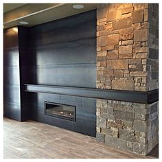 an empty room with a stone fireplace in the center and wood flooring on the other side