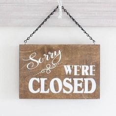 a wooden sign that says sorry we're closed hanging from a chain on the wall