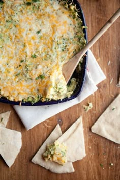 a blue dish filled with cheese and tortilla chips on top of a wooden table