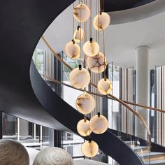 an elegant spiral staircase with marble balls hanging from the railing and circular chandelier