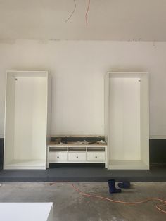 an empty room with two white cabinets and a red wire hanging from the ceiling above it