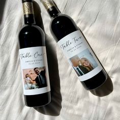 two bottles of wine sitting next to each other on a white sheet covered tablecloth