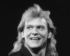 an old black and white photo of a man with long hair smiling at the camera