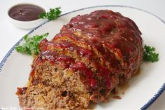 meatloaf with sauce and garnish on a plate next to dipping sauce