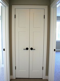 an empty room with two white doors and carpeted flooring in front of it