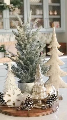 small christmas trees are sitting on a tray in front of a kitchen counter with white cabinets