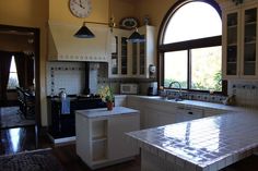 a kitchen with an arched window, white cabinets and counter tops is seen in this image