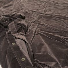 an unmade bed with a jacket on it