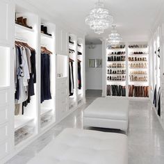 a walk in closet filled with lots of white furniture and shelves full of clothes on hangers