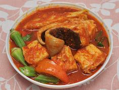 a bowl filled with meat and vegetables on top of a pink tablecloth covered table