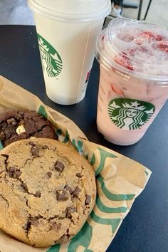 two starbucks drinks and cookies on a table