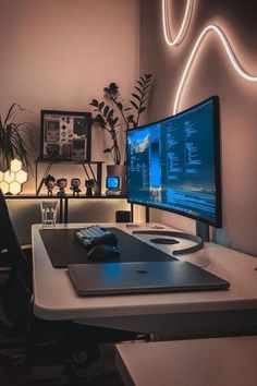 a desk with a computer monitor, keyboard and mouse on it in front of a plant