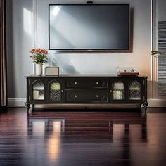 an entertainment center with a flat screen tv mounted on the wall and wooden flooring