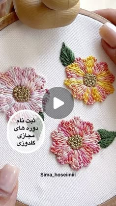 someone is stitching flowers on a piece of fabric