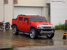 a red hummer truck parked in front of a garage